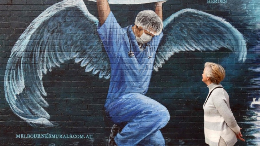 a_woman_looks_at_a_mural_of_a_nurse_with_wings_holding_a_globe_on_international_nurses_day_.jpeg